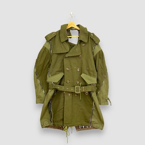 Peut inclure: Un trench-coat vert olive à double boutonnage, avec une ceinture, des poches et des boutons. Le manteau est suspendu à un cintre en bois sur un fond neutre. Le design du manteau comprend des pièces de tissu à motifs.