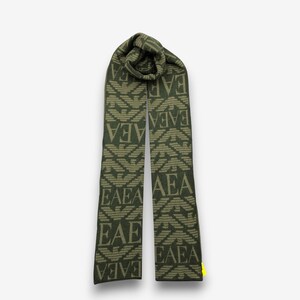 May include: Olive green scarf with a repeating pattern of the letters "EAEA" and a stylized eagle design. The scarf is made of a soft material and is displayed against a white background. The scarf is a fashion accessory.