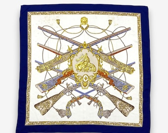 Può includere: Foulard quadrato in seta con bordo blu navy e centro bianco. Il centro presenta fucili antichi incrociati, decorazioni dorate e un emblema centrale con una figura. Il foulard ha un bordo dorato decorativo.