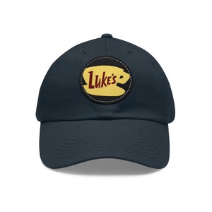May include: A navy blue baseball cap with a yellow and black patch featuring the text "Luke's" in red lettering and a stylised coffee cup.