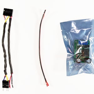 Könnte beinhalten: Ein Satz elektronischer Komponenten für ein Projekt, bestehend aus einer Platine in einer durchsichtigen Plastiktüte, einem schwarzen Stecker mit roten, gelben und blauen Drähten sowie einem einzelnen roten Draht mit einem Stecker.