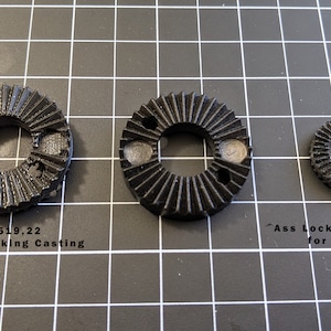 May include: Three black plastic gears, the largest one labeled "R519,22 Ass Locking Casting" and the smallest one labeled "Ass Locking Casting for 701HLV".