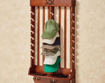 May include: A wall-mounted wooden hat rack with a dark brown finish, featuring a carved letter S in a shield emblem at the top. The rack has vertical slats with side notches for hanging hats, a small storage shelf, and three metal hooks below.