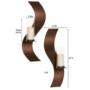 Puede incluir: Dos apliques de pared con acabado en bronce texturizado y un dise&ntilde;o met&aacute;lico curvo en forma de onda. Cada uno cuenta con un soporte de vidrio cil&iacute;ndrico transparente que contiene una vela de pilar blanca. Las dimensiones son 68,58 cm de alto, 25,4 cm de ancho, 15,24 cm de profundidad, con vidrio de 24,13 cm de alto y 10,16 cm de di&aacute;metro.