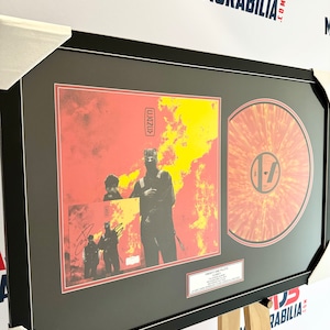 May include: A framed record album with a red, orange, and yellow splatter design. The album cover features a band with a fiery background. The album title is "Thirty One Pilots" and the band name is "YODZA".