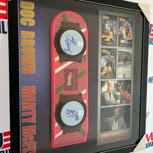May include: A framed display featuring a replica of the DeLorean time machine from the Back to the Future films. The display includes autographed photos of Christopher Lloyd and Michael J. Fox, as well as film posters.