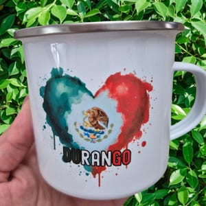 May include: White enamel mug with a silver rim and handle. The mug features a heart-shaped design in the colors of the Mexican flag, with the state's emblem and the word "DURANGO" in black and red.
