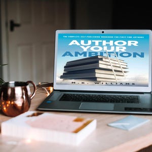 Può includere: Un computer portatile aperto su una copertina di libro con il titolo "Author Your Ambition: The Complete Self-Publishing Workbook for First-Time Authors" di M.K. Williams. La copertina presenta una pila di libri con una scala appoggiata a loro, su uno sfondo di cielo blu con nuvole.