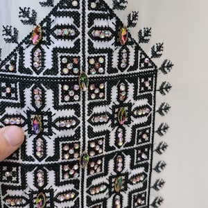 May include: White fabric with black embroidery and iridescent rhinestones in a geometric pattern. The embroidery features a repeating design of squares and diamonds.
