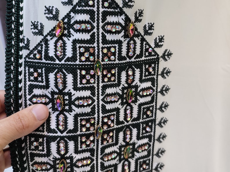 May include: White fabric with black embroidery and iridescent rhinestones in a geometric pattern. The embroidery features a repeating design of squares and diamonds.