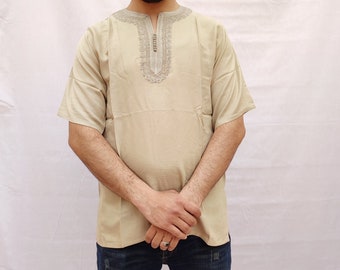 May include: A beige short-sleeved shirt with an embroidered neckline. The embroidery is a light grey color and features a geometric pattern.