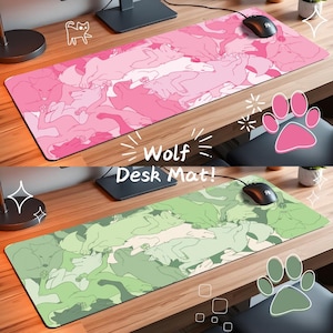 May include: Two desk mats featuring a design of sleeping wolves. The top mat is pink with white outlines and the bottom mat is green with white outlines. Both mats have the text "Wolf Desk Mat!" printed on them.