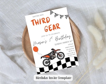 May include: A white birthday invitation with orange and black accents. The text reads "Third Gear" and "Mason's 3rd Birthday." A cartoon motorcycle and checkered flag design are also featured. The invitation is on a wooden plate.