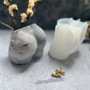 May include: A white silicone mould of a human body shape. The mould is used to create a concrete sculpture. The sculpture is shown in the image, painted in a grey and white marbled pattern.