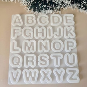 Puede incluir: Molde de silicona blanco con las letras del alfabeto de la A a la Z en moldes individuales.
