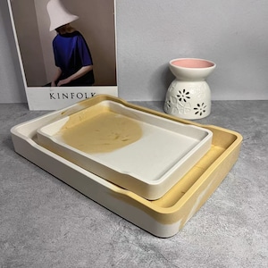 May include: Two rectangular trays, one nested inside the other. The larger tray is white with brown marbling, and the smaller tray is brown with white marbling.