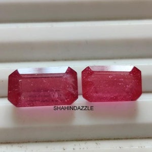 Może przedstawiać: Dwa różowe, prostokątne kamienie szlachetne o fasetowanym szlifie. Kamienie szlachetne znajdują się na białej powierzchni.