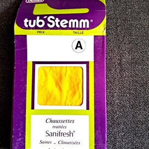 Peut inclure: Un paquet de chaussettes jaunes, étiqueté "tub'Stemm" avec la taille "A". L'emballage est violet et vert avec les mots "Chaussettes traitées Sanifresh" imprimés dessus.