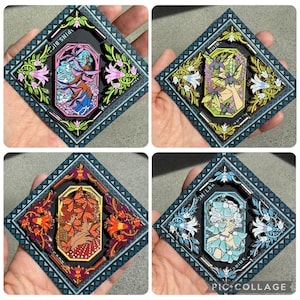 May include: Four square enamel pins with detailed designs. Each pin has a central figure in a decorative frame, surrounded by floral and geometric patterns. The colour palettes include blues, pinks, oranges, and greens. The text "PINS.BIG" and "SMILAN" are visible.