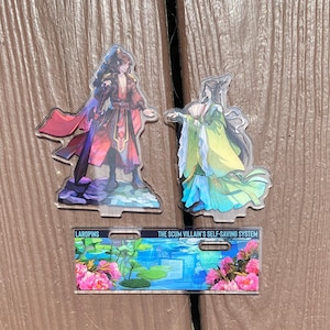 May include: Three acrylic character standees featuring anime-style illustrations. One figure wears red and black robes, another wears green and blue robes. A rectangular standee displays the text "THE SCUM VILLAIN'S SELF-SAVING SYSTEM" with floral and water lily graphics.