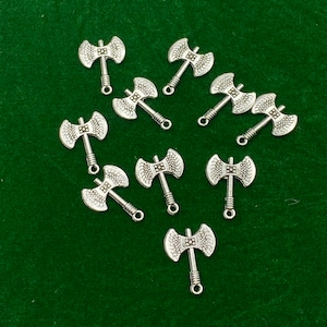 May include: Twelve silver axe charms with a detailed design. The charms have a loop at the top for attaching to jewelry or other crafts.