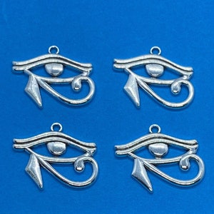 Puede incluir: Cuatro abalorios plateados en forma de Ojo de Horus, un símbolo egipcio antiguo. Cada abalorio tiene un bucle en la parte superior para sujetarlo a un collar o pulsera.
