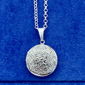 Pequeno medalhão de foto redondo prateado com design detalhado de flores com colar.