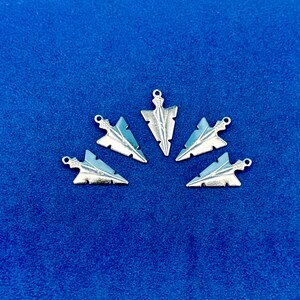May include: Five silver arrowhead charms arranged in a semi-circle on a blue background.