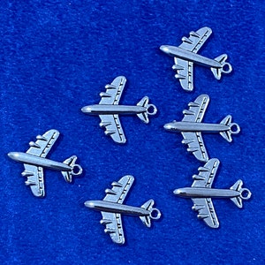 May include: Six silver airplane charms with a detailed design. The charms are perfect for adding a touch of whimsy to jewelry or crafts.