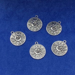 May include: Five silver-toned charms featuring a sun and moon design with zodiac symbols around the perimeter.