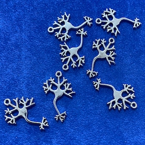 Könnte beinhalten: Ein Set aus sieben silbernen Anhänger-Anhängern in Form von stilisierten Neuronen. Die Anhänger sind filigran und detailliert gearbeitet, mit einer Vielzahl von verzweigten Mustern.