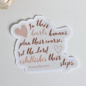 May include: A sticker with a pink heart and the text "In their hearts humans plan their course, but the Lord establishes their steps. Proverbs 16:9"
