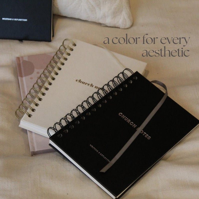 May include: A selection of spiral-bound notebooks in different colours. The notebooks include a black notebook with the text "CHURCH NOTES" and a grey ribbon, a white notebook with the text "church notes", and a pink notebook. The image also includes the text "a colour for every aesthetic".