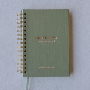 May include: Sage green spiral-bound notebook with gold-colored metal binding. The cover features the words "church notes" in a copper-colored font, with the phrases "steadfast and sustained" and "writing & reflection" below.
