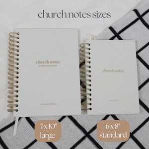 May include: Two spiral-bound notebooks with the text "church notes" in gold lettering. The larger notebook is 17.8x25.4 cm, and the smaller is 15.2x20.3 cm. The notebooks are white with gold spiral binding and a white ribbon bookmark.