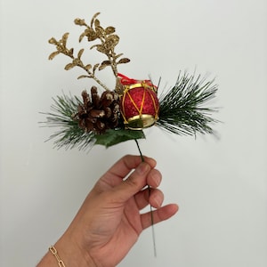 May include: A green pine sprig with a gold glitter branch, a brown pine cone, and a red and gold glitter drum ornament.