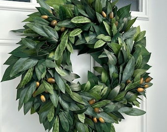 Può includere: Una ghirlanda di rami di ulivo verdi con piccole olive marroni. La ghirlanda è fatta di foglie artificiali ed è perfetta per decorare una porta o un muro.