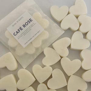 May include: A pack of 16 heart-shaped soy wax melts in a white bag. The bag has a label that says "SEAL SCENTS CAFE ROSE" and "HAND POURED SOY WAX MELT".