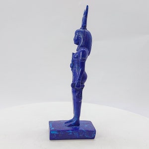 Op de afbeelding: Een blauw lapis lazuli beeld van een Egyptische godin met een hoofdtooi. Het beeld staat op een voetstuk van hetzelfde materiaal.