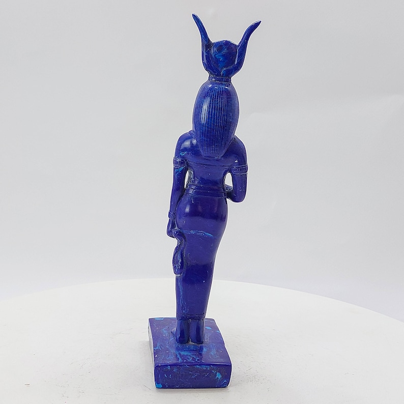 Op de afbeelding: Een blauw lapis lazuli beeld van een Egyptische godin met een hoofdtooi. Het beeld staat op een rechthoekige basis.