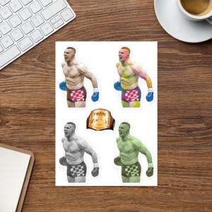 May include: A set of four stickers featuring a fighter in different poses. The fighter is wearing red, white and blue checkered shorts and blue boxing gloves. The stickers also include a gold championship belt with the word "RADES" on it.