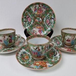 Op de afbeelding: Een set van vier porseleinen theekopjes en schoteltjes met een traditioneel Chinees ontwerp. De kopjes en schoteltjes zijn versierd met een kleurrijk bloemenpatroon en tonen scènes van mensen in traditionele kleding. De kopjes en schoteltjes zijn in uitstekende staat.