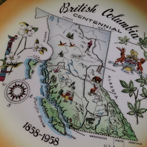 May include: A vintage ceramic plate depicting a map of British Columbia, Canada, with the text "British Columbia Centennial 1858-1958". The plate is decorated with floral motifs and a compass.