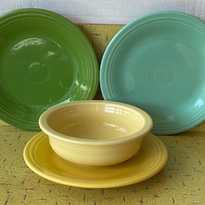 Puede incluir: Tres platos de cerámica en verde, verde azulado y amarillo. Los platos son todos del mismo tamaño y tienen un diseño simple y elegante.