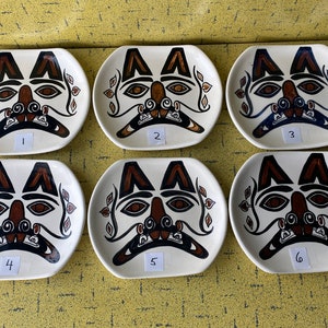 May include: Six white ceramic plates with brown and black stylised animal faces. Each plate is numbered 1 through 6.
