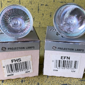 Può includere: Due lampade di proiezione GE, modelli FHS ed EFN, con lampadine in vetro trasparente. La lampada FHS è da 300W, 82V, e la lampada EFN è da 75W, 12V. Entrambe sono nelle loro scatole originali.