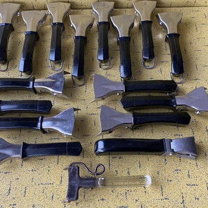 Può includere: Una collezione di 15 manici per pentole neri e argentati con un design unico. I manici sono in metallo e hanno un'impugnatura in plastica nera.