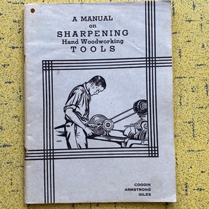 May include: A vintage manual titled "A Manual on Sharpening Hand Woodworking Tools." The cover features a black and white illustration of a person using a sharpening machine. The manual's title is in bold, black font.