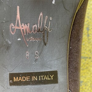 May include: Close-up of the bottom of a brown suede shoe with the label "Amalfi by Rangoni" and "Made in Italy" printed on the sole. The shoe size is 8S.