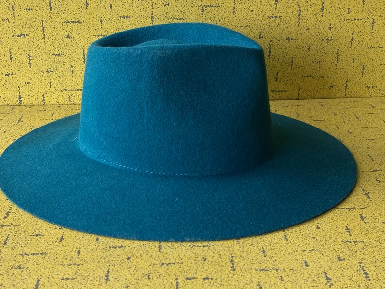 May include: A teal blue fedora hat with a wide brim.